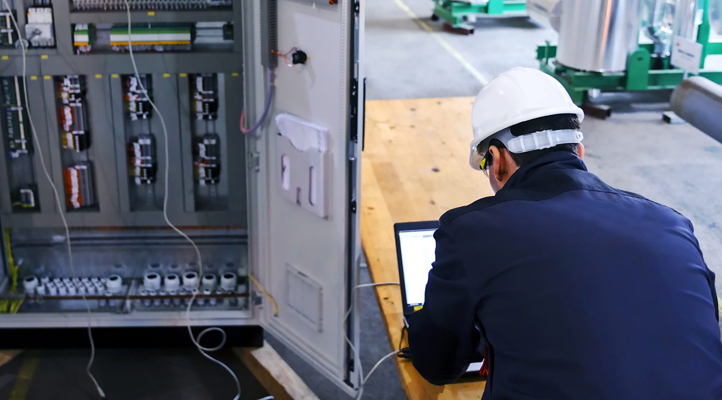 Een POWARE Industrial Automation B.V. engineer werkt aan een productie machine PLC SCADA DCS besturingsysteem.